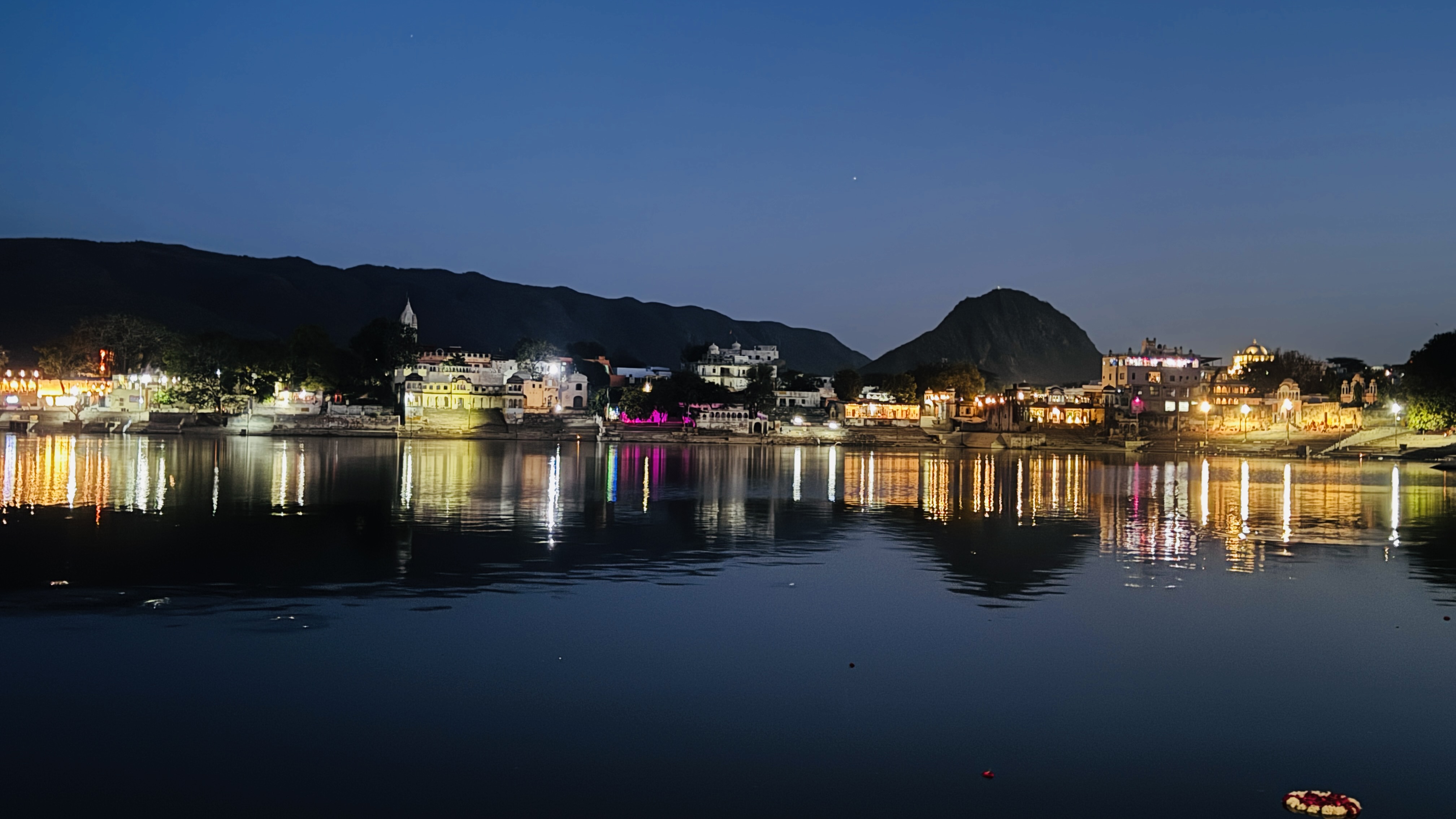 Pushkar ghats lit up at night, reflected in the lake